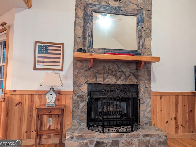 room details featuring wood-type flooring, a stone fireplace, and wooden walls