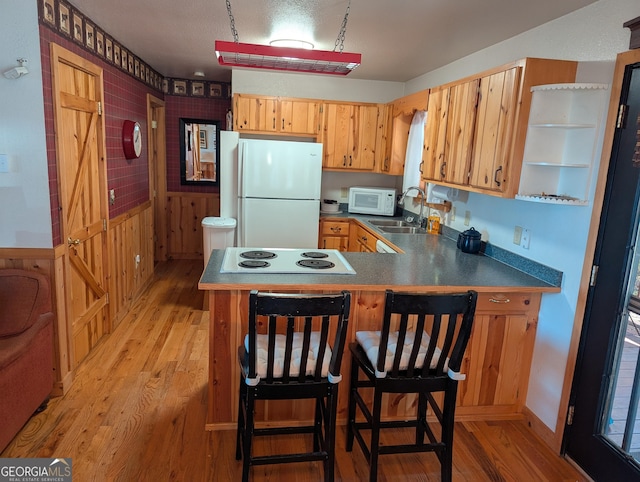 kitchen with light hardwood / wood-style floors, sink, white appliances, and kitchen peninsula