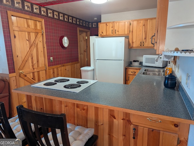 kitchen featuring white appliances, kitchen peninsula, and sink