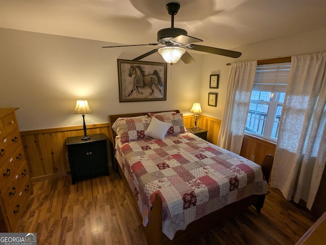 bedroom with dark hardwood / wood-style floors, ceiling fan, and wood walls