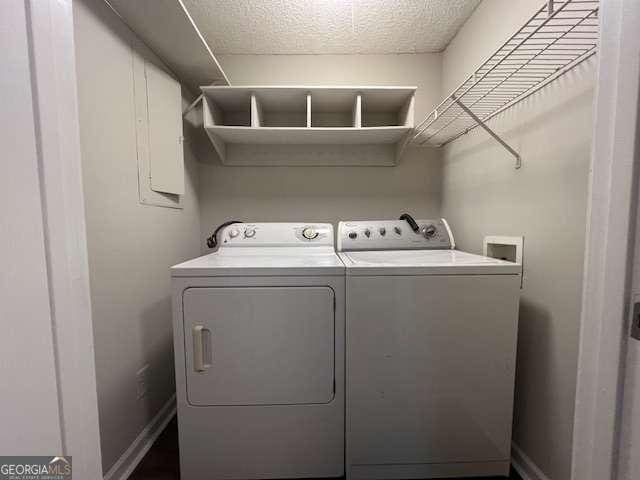 laundry area with independent washer and dryer and a textured ceiling