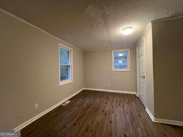 empty room featuring crown molding, dark wood-type flooring, and a textured ceiling