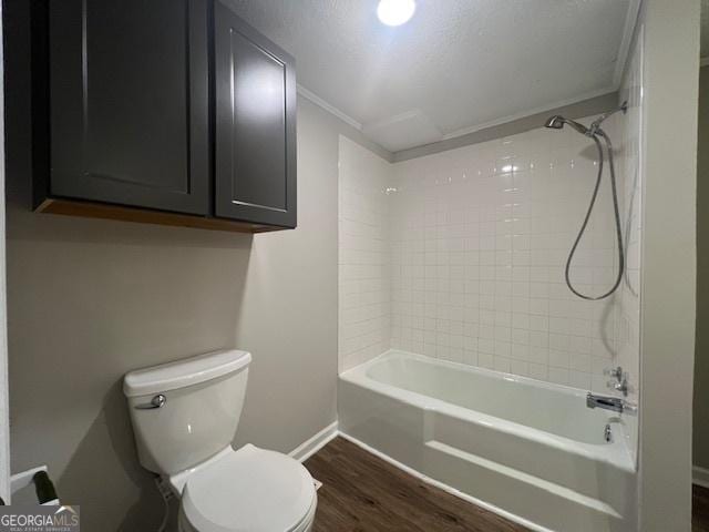 bathroom featuring hardwood / wood-style flooring, ornamental molding, toilet, and tiled shower / bath combo