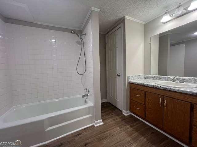 bathroom with crown molding, a textured ceiling, vanity, tiled shower / bath combo, and hardwood / wood-style flooring