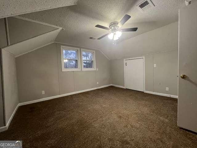 additional living space with ceiling fan, vaulted ceiling, a textured ceiling, and dark colored carpet