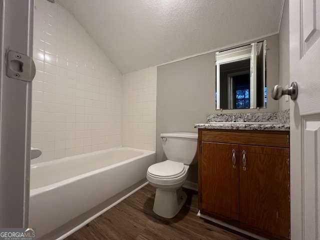 full bathroom with vaulted ceiling, hardwood / wood-style flooring, tiled shower / bath combo, vanity, and toilet