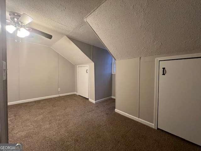 bonus room with dark colored carpet, vaulted ceiling, ceiling fan, and a textured ceiling