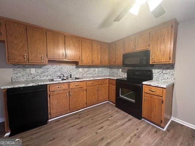 kitchen featuring sink, wood-type flooring, black appliances, a textured ceiling, and decorative backsplash