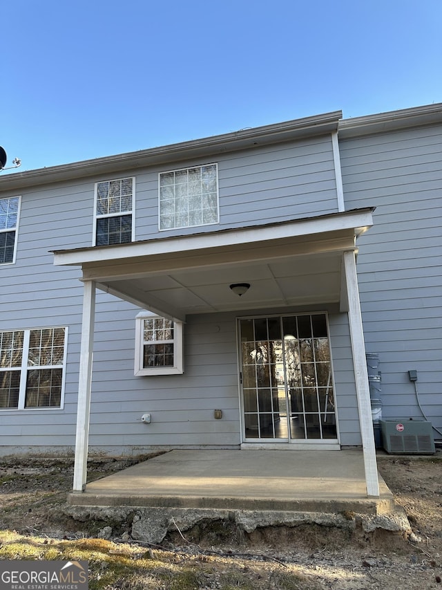 view of exterior entry with a patio and central air condition unit