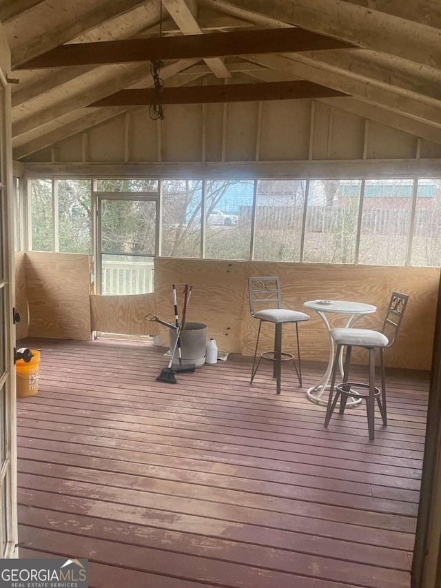 unfurnished sunroom featuring lofted ceiling with beams