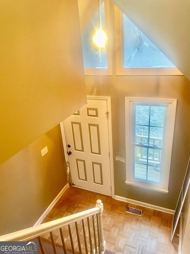 doorway with parquet floors and high vaulted ceiling