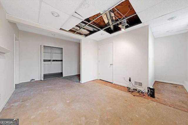 spare room with concrete floors and a drop ceiling