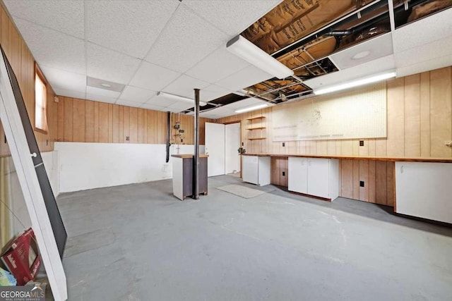 basement with a paneled ceiling and wood walls