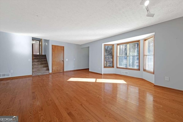 spare room with a textured ceiling and light wood-type flooring