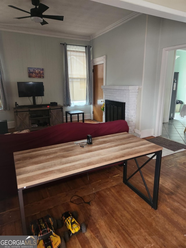 interior space with crown molding, a brick fireplace, hardwood / wood-style floors, and ceiling fan