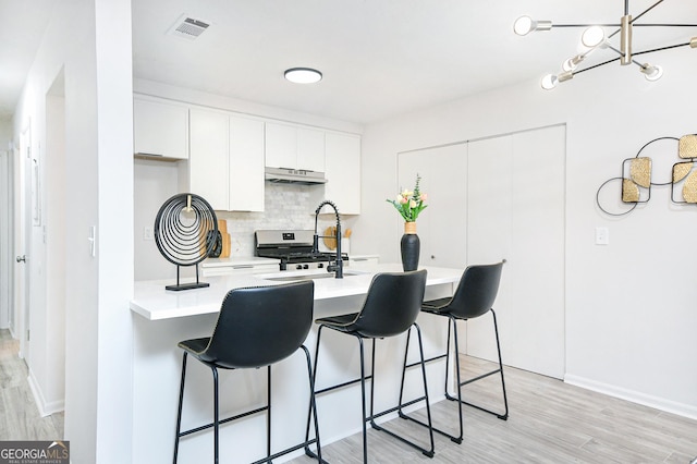 kitchen featuring sink, white cabinetry, backsplash, stainless steel range, and light wood-type flooring