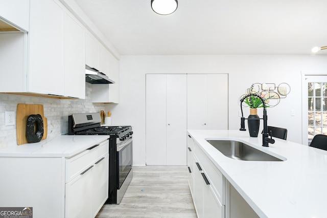 kitchen featuring white cabinetry, sink, light stone countertops, and stainless steel range with gas stovetop