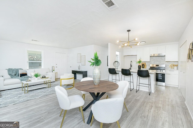 dining room featuring a notable chandelier, light hardwood / wood-style floors, and sink