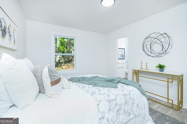 bedroom featuring ensuite bath and wood-type flooring