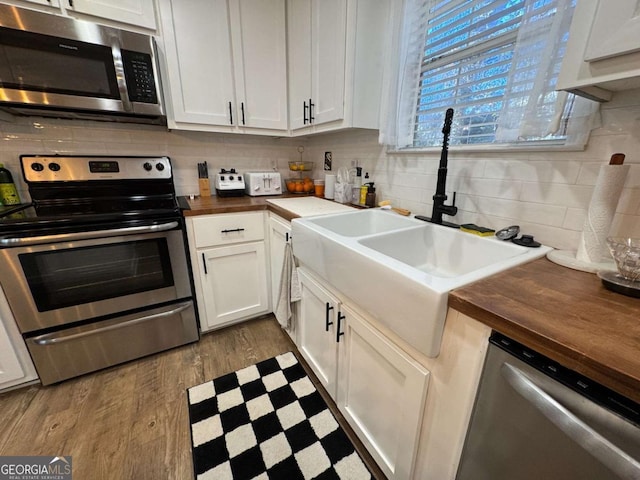 kitchen with stainless steel appliances, sink, white cabinets, and wooden counters