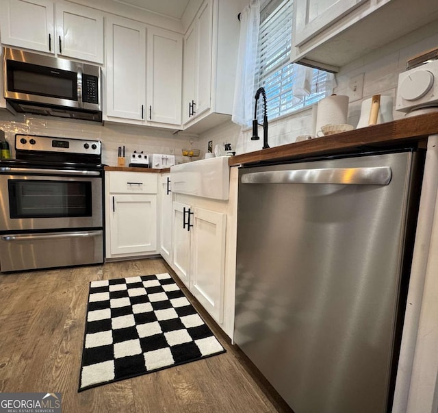 kitchen with white cabinetry, wooden counters, backsplash, stainless steel appliances, and light hardwood / wood-style flooring