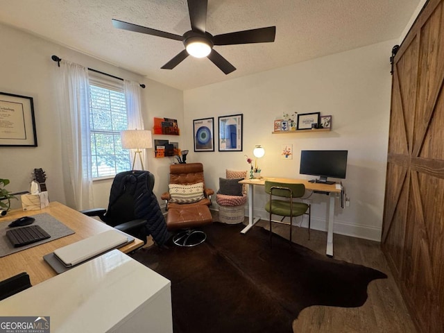 office featuring hardwood / wood-style flooring, ceiling fan, a barn door, and a textured ceiling