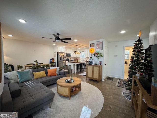 living room with ceiling fan, dark hardwood / wood-style flooring, and a textured ceiling