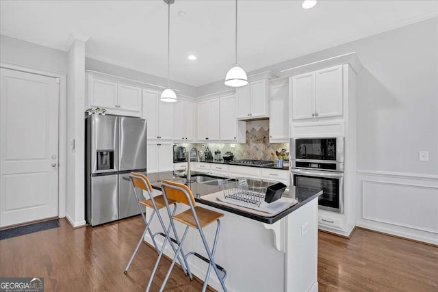 kitchen featuring stainless steel appliances, a kitchen breakfast bar, an island with sink, and white cabinets