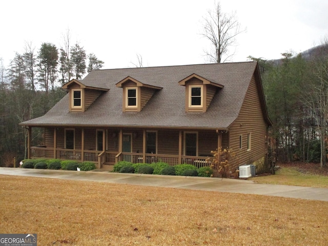 view of front facade featuring covered porch, a front yard, and central air condition unit