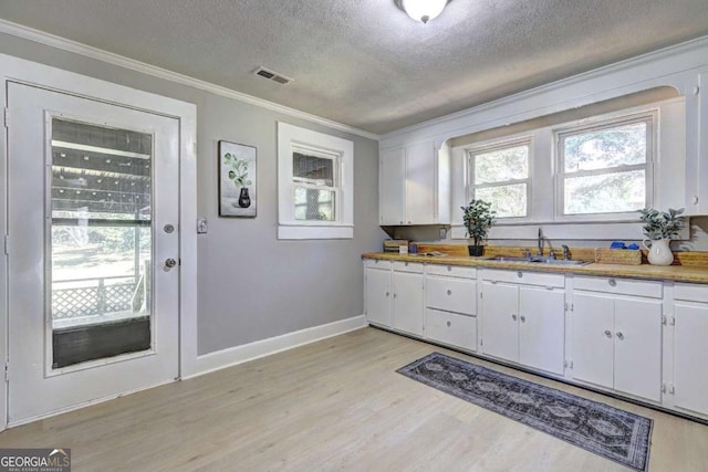 kitchen with crown molding, sink, white cabinets, and light wood-type flooring