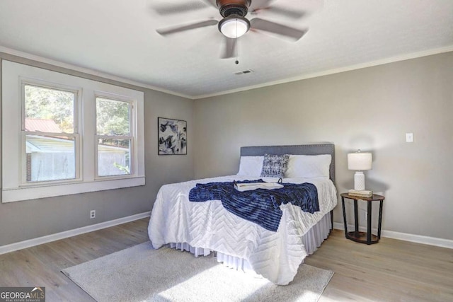 bedroom featuring crown molding, light hardwood / wood-style floors, and ceiling fan