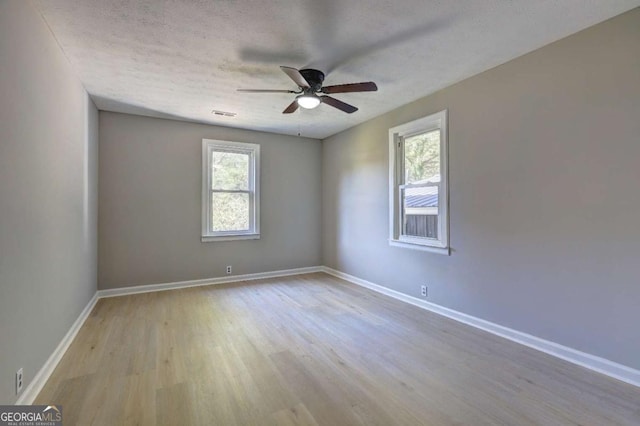 empty room featuring ceiling fan, light hardwood / wood-style floors, and a textured ceiling