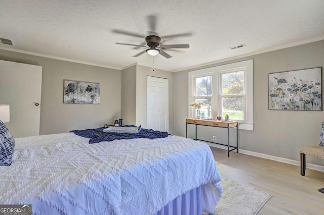 bedroom featuring crown molding, a textured ceiling, and light hardwood / wood-style flooring