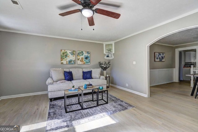 living room with crown molding, light hardwood / wood-style flooring, and ceiling fan