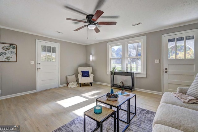 living room featuring crown molding, ceiling fan, a wealth of natural light, and light wood-type flooring