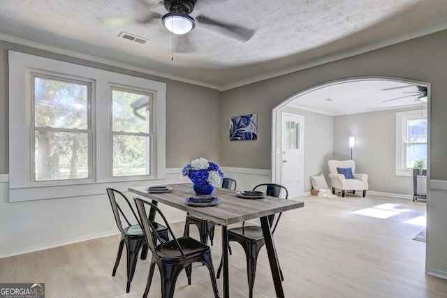 dining space featuring ceiling fan, crown molding, light hardwood / wood-style floors, and a textured ceiling