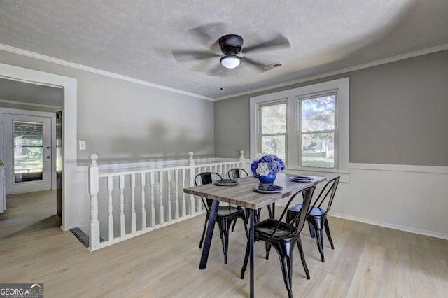 dining area with a healthy amount of sunlight, ornamental molding, light hardwood / wood-style floors, and a textured ceiling