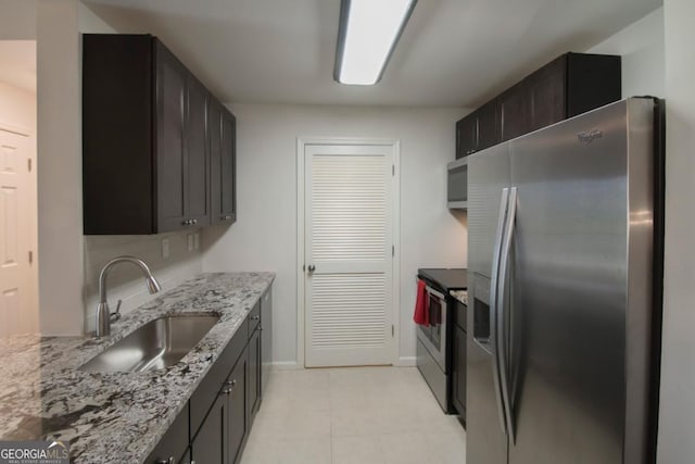 kitchen with dark brown cabinetry, appliances with stainless steel finishes, sink, and light stone counters