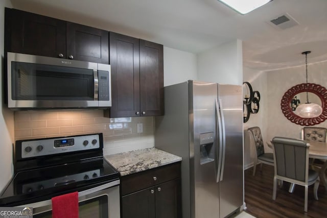 kitchen with dark brown cabinetry, stainless steel appliances, dark hardwood / wood-style floors, and backsplash