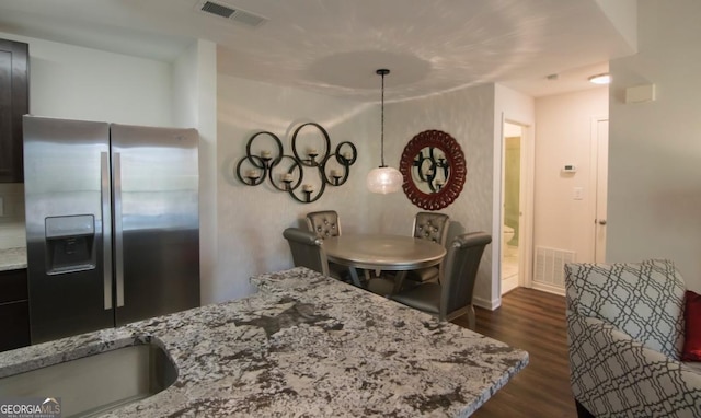 kitchen with stainless steel refrigerator with ice dispenser, light stone countertops, pendant lighting, and dark hardwood / wood-style flooring