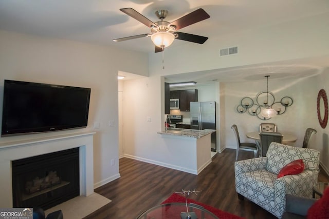 living room with ceiling fan with notable chandelier and dark hardwood / wood-style floors