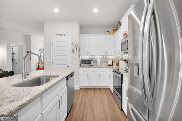 kitchen with light stone counters, appliances with stainless steel finishes, sink, and white cabinets