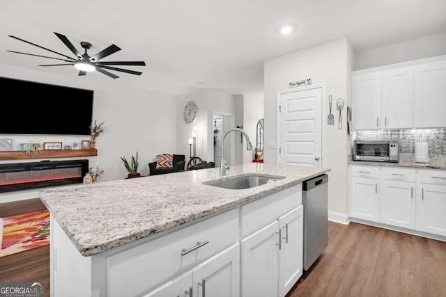 kitchen with dishwasher, white cabinetry, sink, and a kitchen island with sink