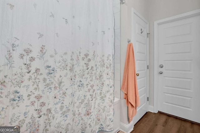 bathroom with shower / tub combo and hardwood / wood-style floors