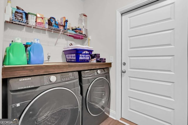 clothes washing area featuring hardwood / wood-style flooring and washing machine and clothes dryer