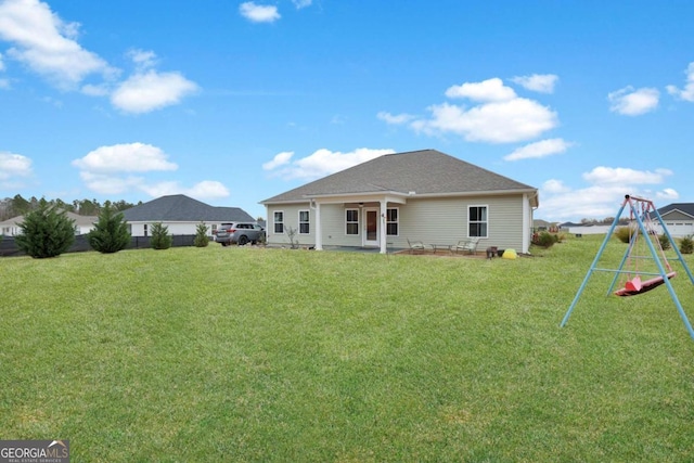 back of house featuring a yard and a playground