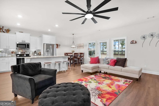 living room featuring ceiling fan, sink, and light hardwood / wood-style flooring