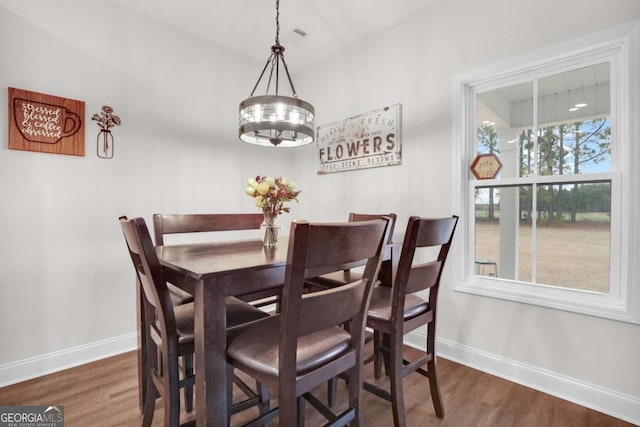 dining area with dark wood-type flooring and a chandelier