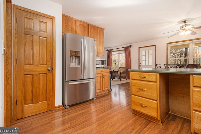 kitchen with light wood-type flooring, ceiling fan, and appliances with stainless steel finishes