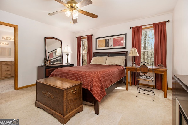 bedroom with multiple windows, light colored carpet, ceiling fan, and ensuite bathroom